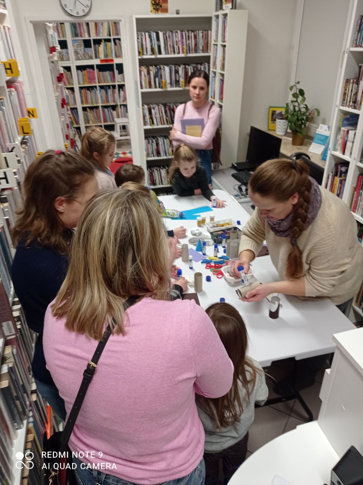 Bibliotekarka pokazuje dzieciom jak wykonać pracę plastyczną