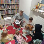 Bibliotekarka pokazuje plansze o wielorybku, widoczna grupa dzieci