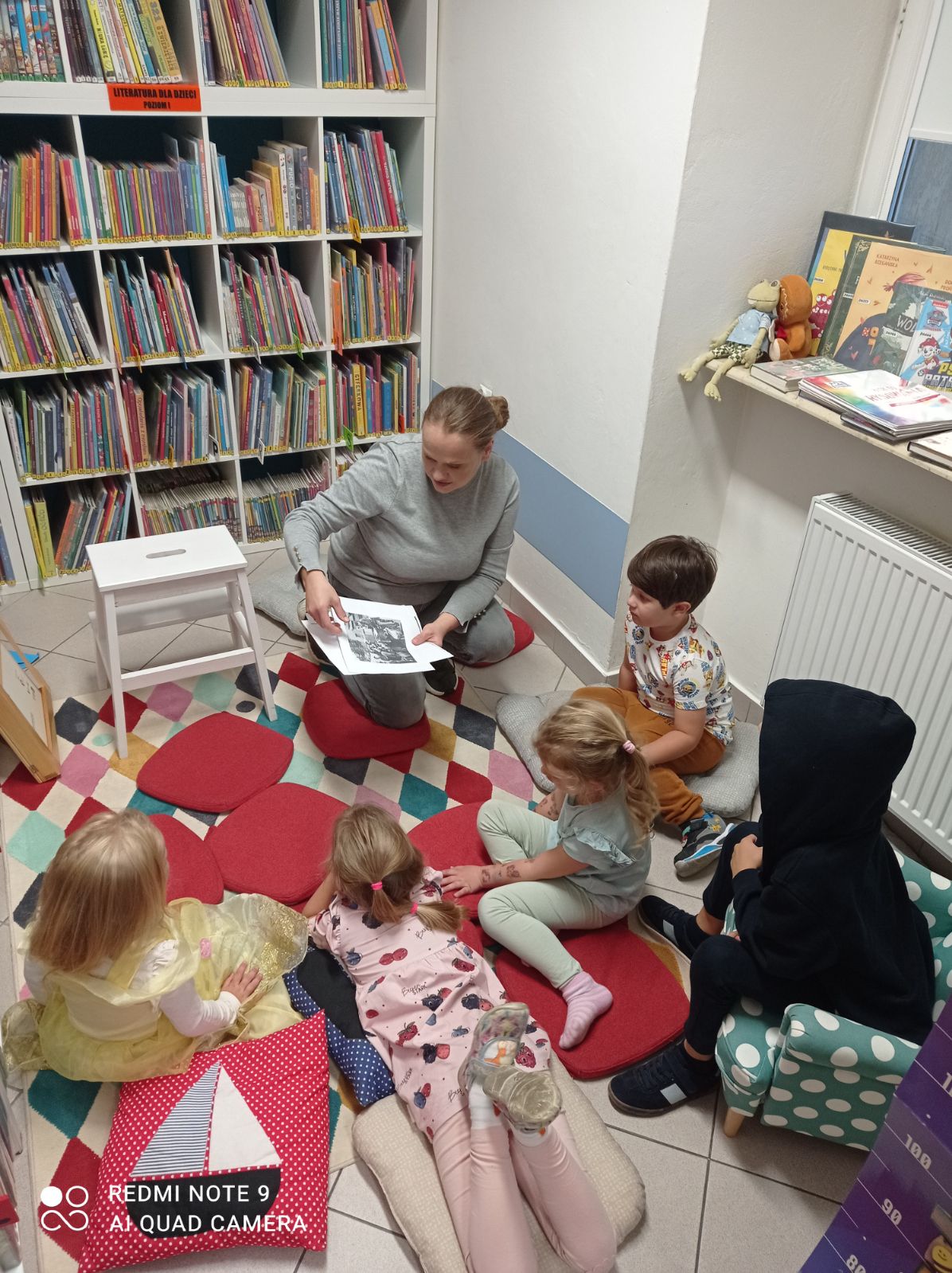 Bibliotekarka pokazuje plansze o wielorybku, widoczna grupa dzieci