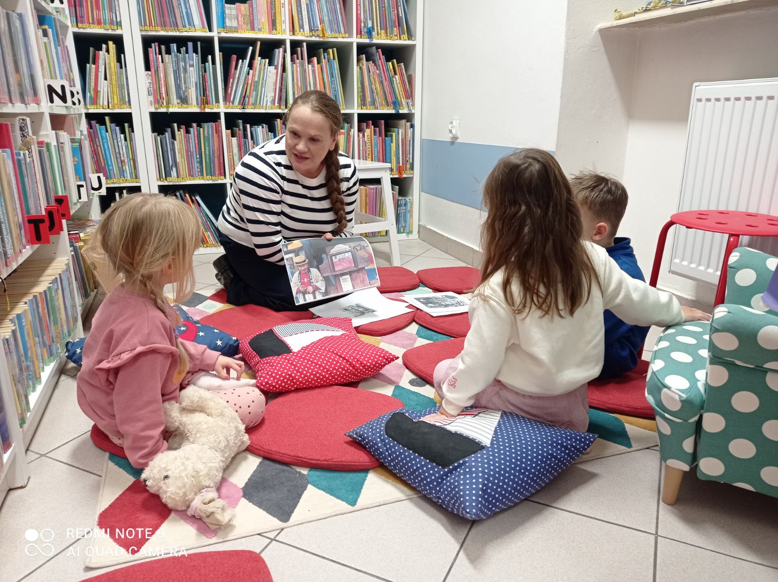 Bibliotekarka pokazuje dzieciom plansze bajki o myszce