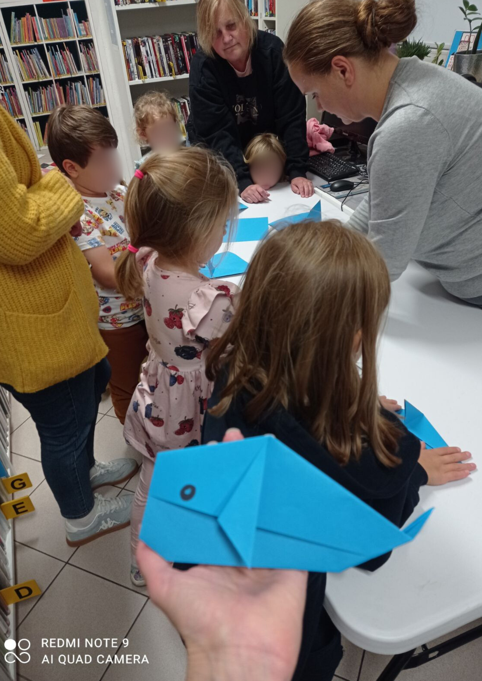 Grupa dzieci podczas wykonywania pracy plastycznej. Na pierwszym planie złożony wieloryb z origami