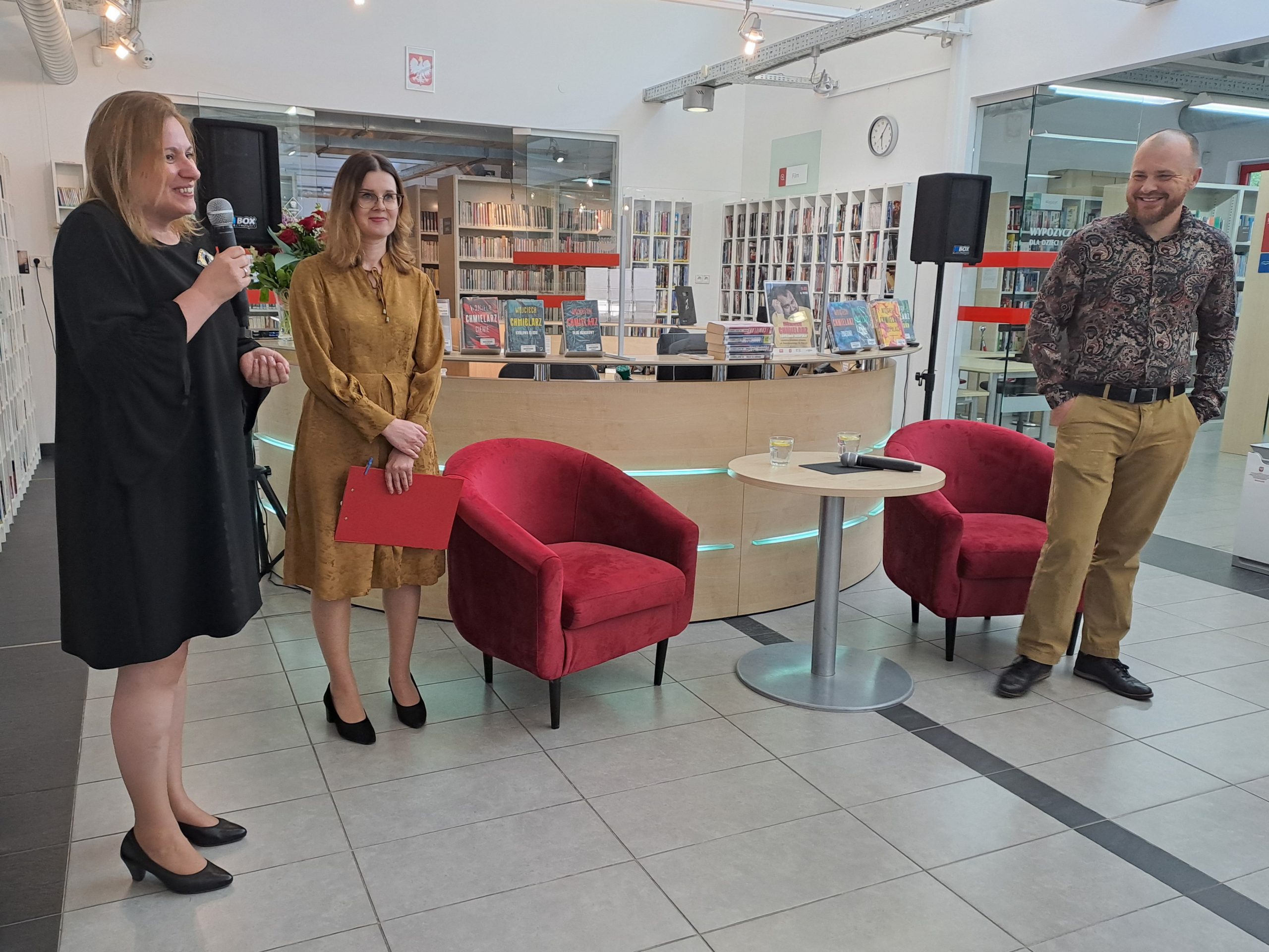 Dyrektor biblioteki i prowadząca spotkanie witają Wojciecha Chmielarza.