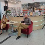 Wojciech Chmielarz i prowadząca siedzą na czerwonych fotelach z mikrofonami w rękach