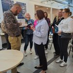 Sesja autografów z Wojciechem Chmielarzem - autor podpisuje książki, widać uczestników spotkania w kolejce