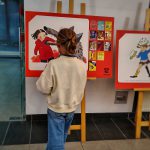 Dziewczynka stoi przed jedną z plansz wystawy w holu biblioteki