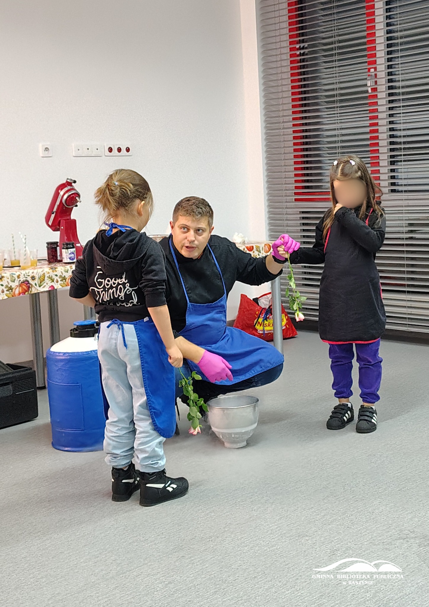 Podczas warsztatów kuchni molekularnej - prowadzący z dwiema uczestniczkami mrozi róże w azocie
