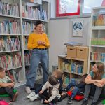 Bibliotekarka pokazuje papierowego kraba, dzieci i nauczycielka obserwują