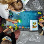 Dzieci siedzą przy planszy przedstawiającej podwodny świat, układają klocki