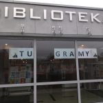 Zbliżenie na front biblioteki z hasłem "Tu gramy"