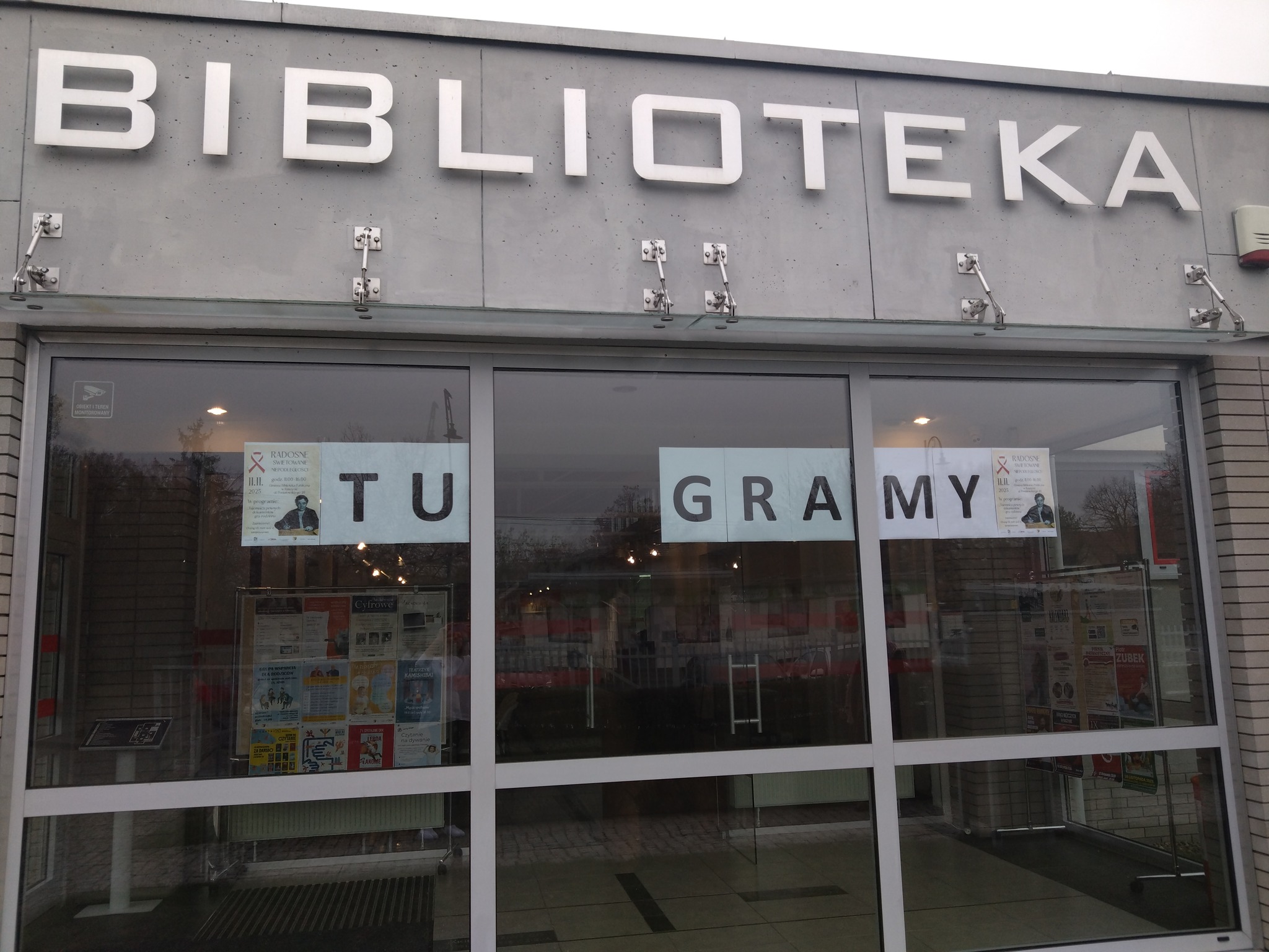 Zbliżenie na front biblioteki z hasłem "Tu gramy"