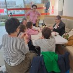 Warsztaty tworzenia kokard patriotycznych - grupa uczestników siedzi przy stole