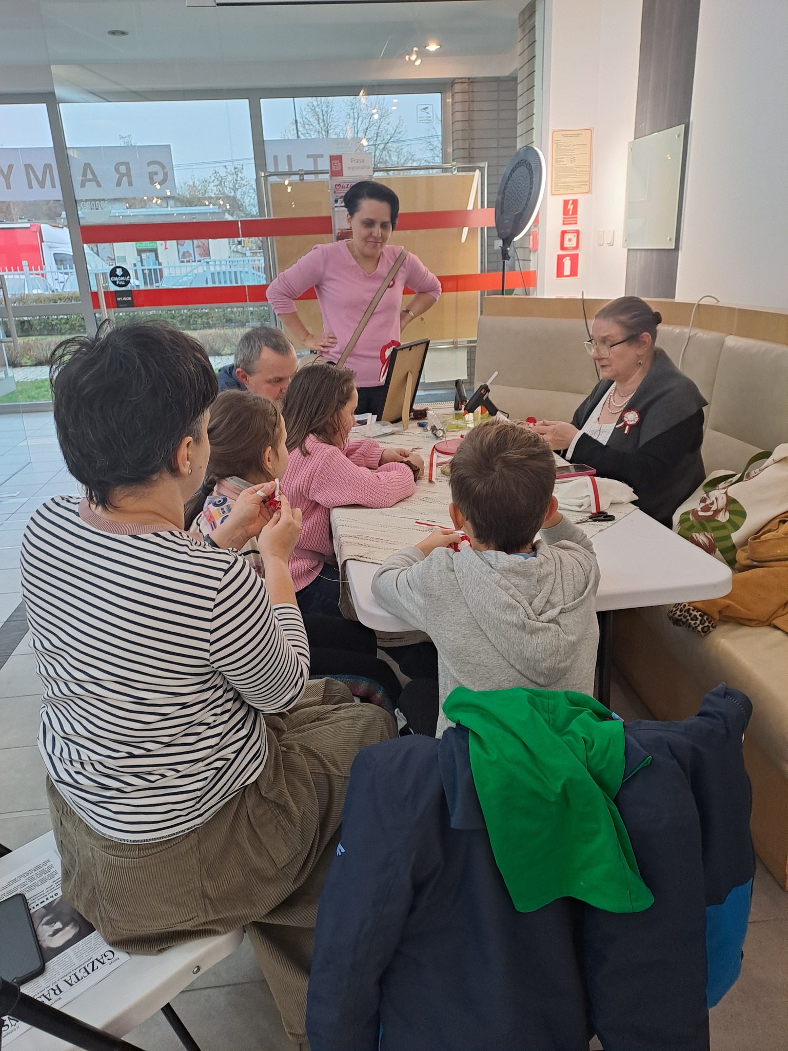 Warsztaty tworzenia kokard patriotycznych - grupa uczestników siedzi przy stole