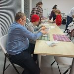 Uczestnicy przy stołach mieszają masę papierową