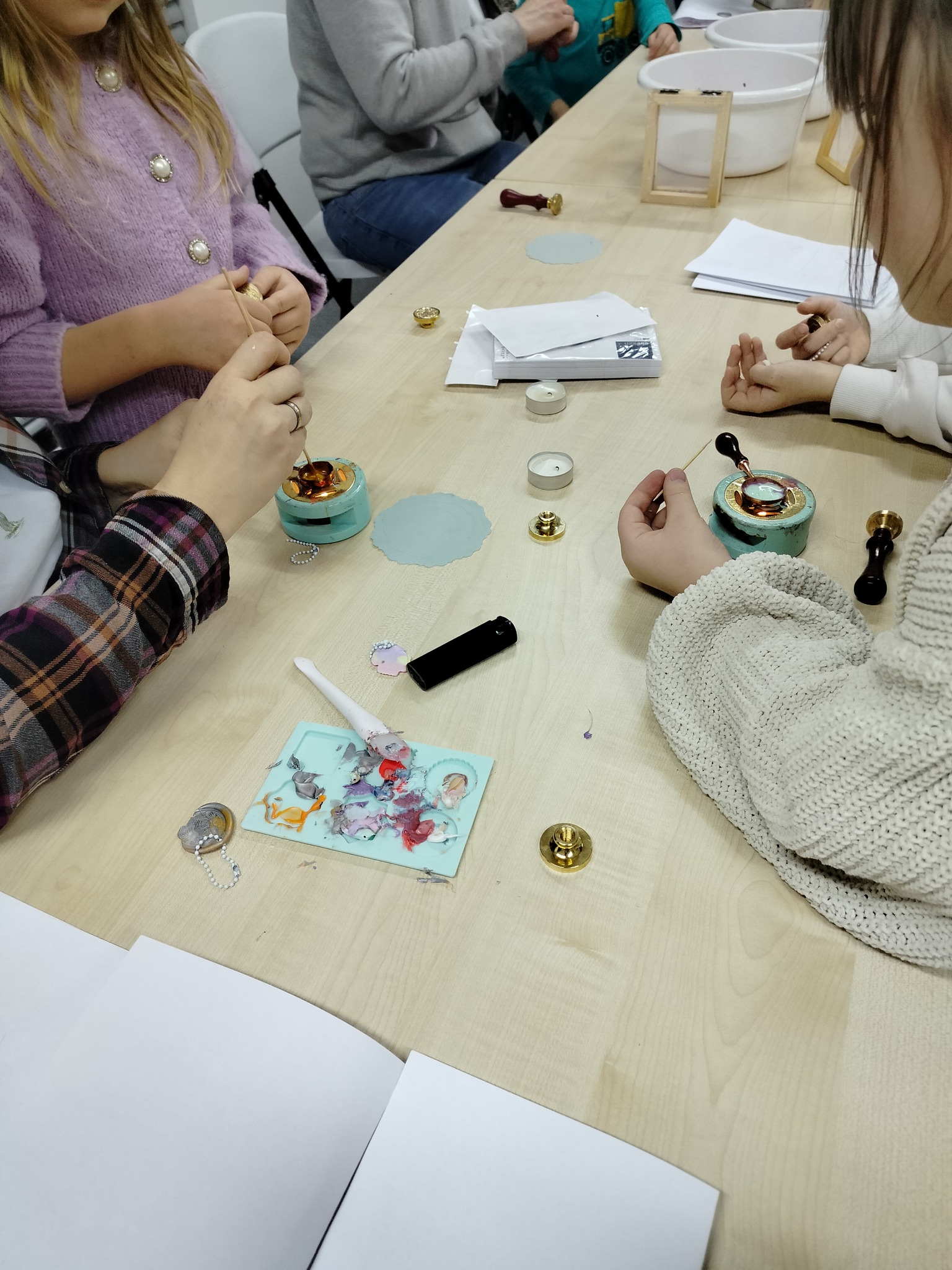 Uczestnicy podczas odciskania pieczęci w kolorowym wosku