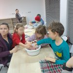 Uczestnicy przy stołach mieszają masę w misce