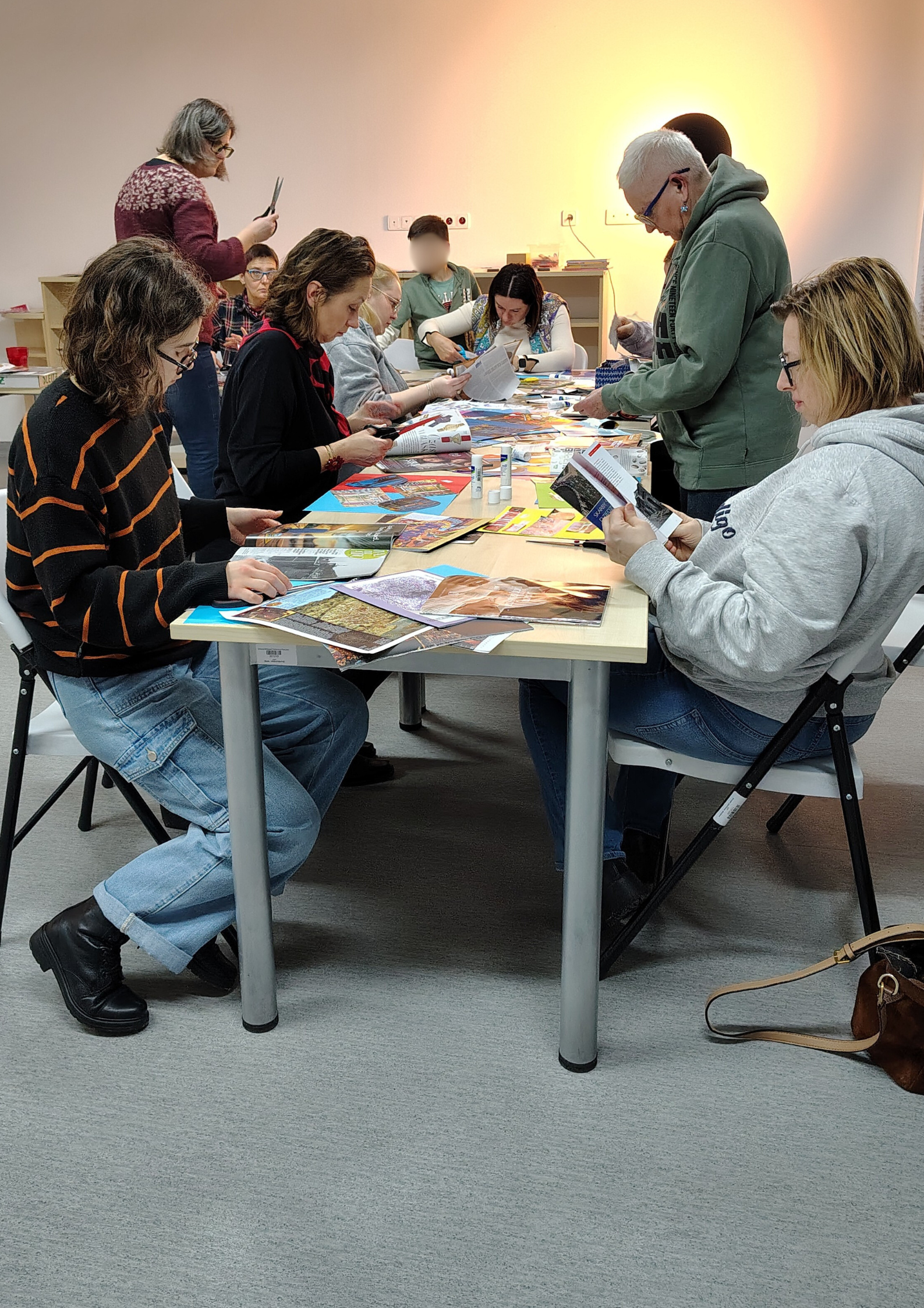 Grono uczestników sieci przy stołach z wycinankami z gazet