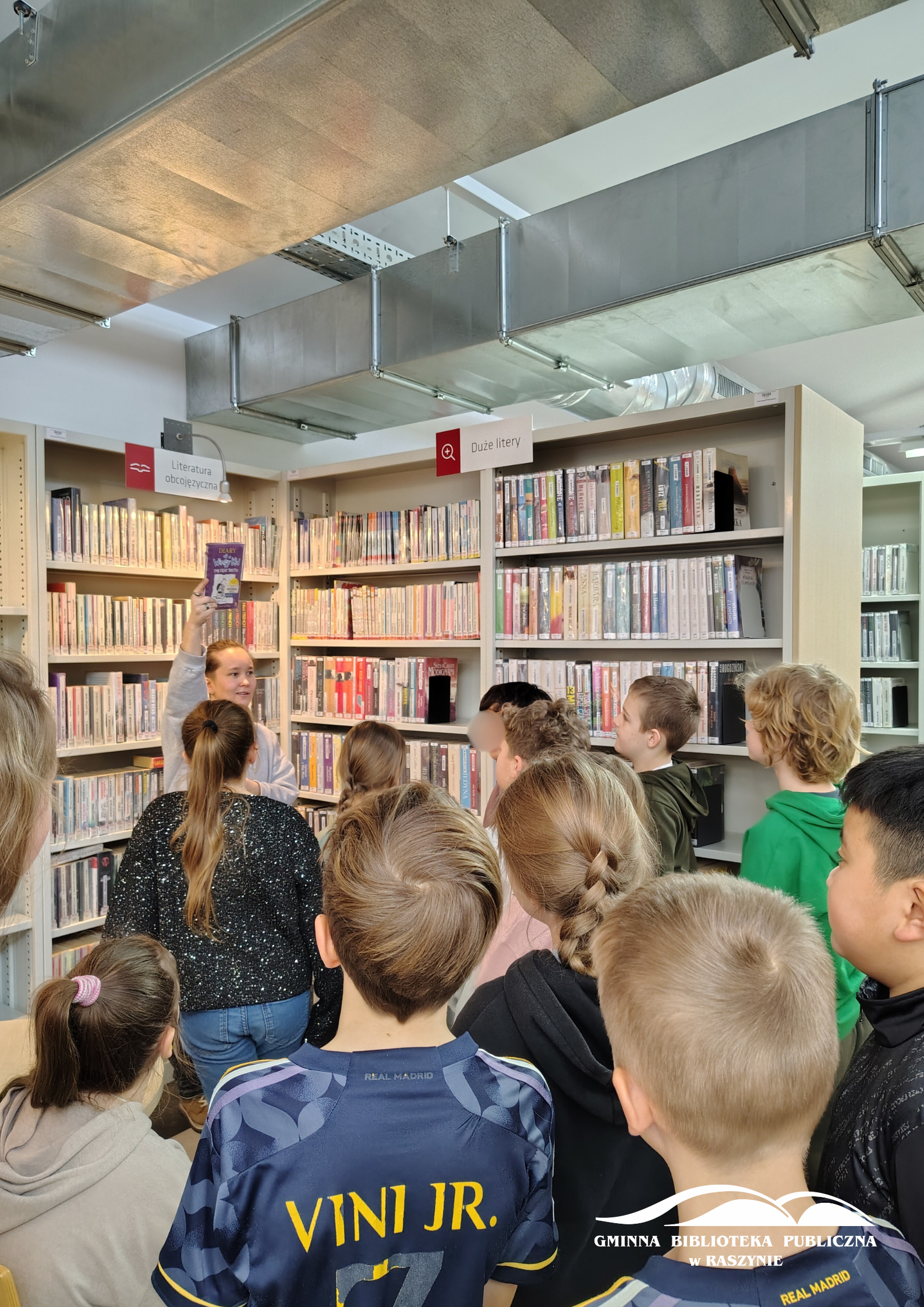 Uczniowie zwiedzają dział z książkami anglojęzycznymi