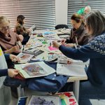 Grupa uczestników warsztatów kolażowych podczas pracy nad kolażami