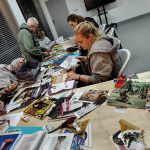 Zbliżenie na stół z uczestnikami i pociętymi gazetami