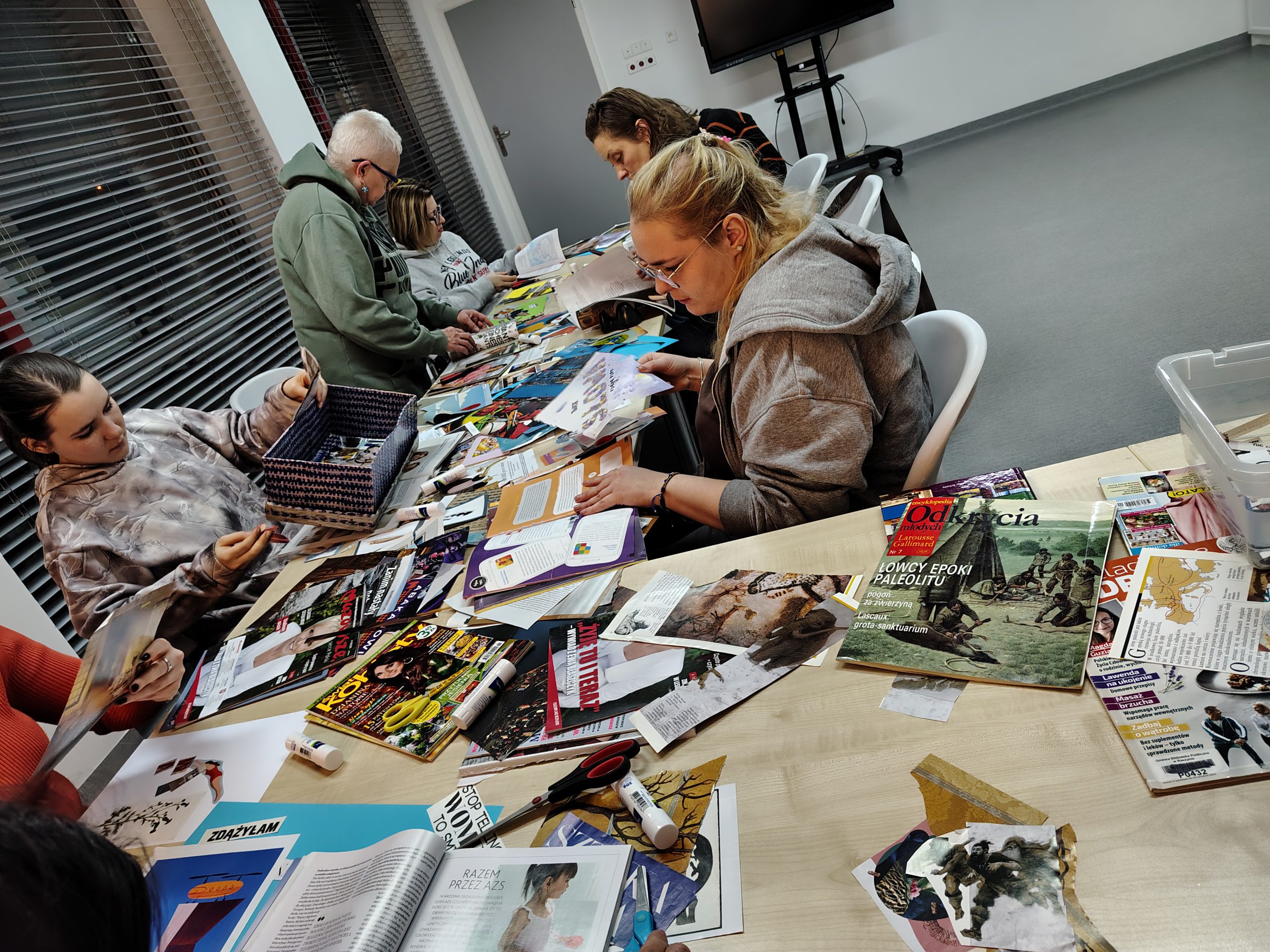 Zbliżenie na stół z uczestnikami i pociętymi gazetami