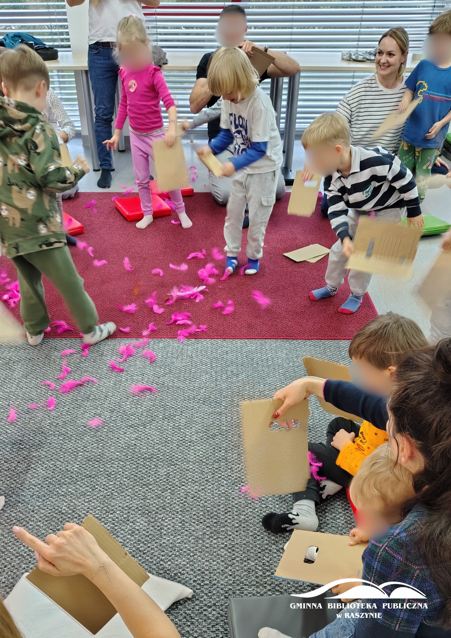 Uczestnicy warsztatów na dywanie z piórkami