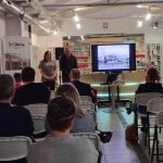 Dyrektor biblioteki przedstawia gościa, widoczna publiczność