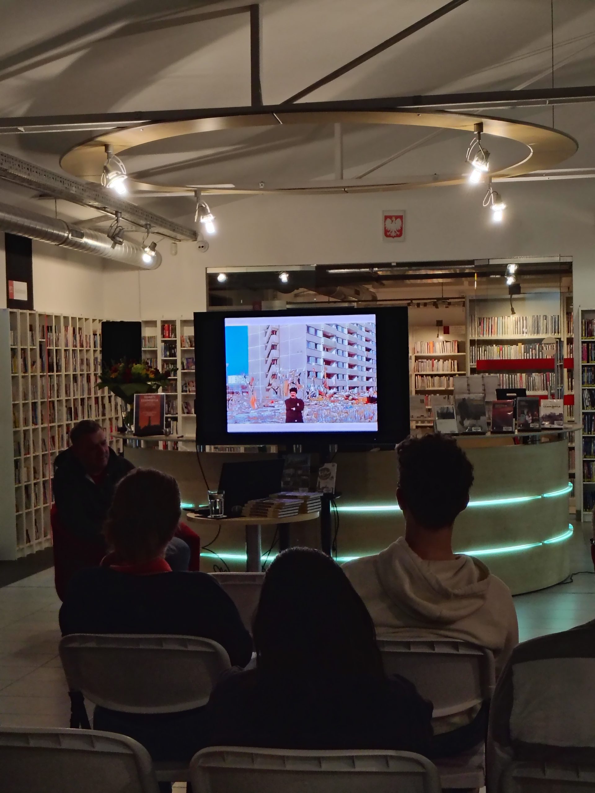 Borys Tynka siedzi na fotelu, widoczny ekran z fotografią bloków w Prypeci