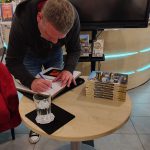 Autor wpisuje się do bibliotecznej księgi pamiątkowej