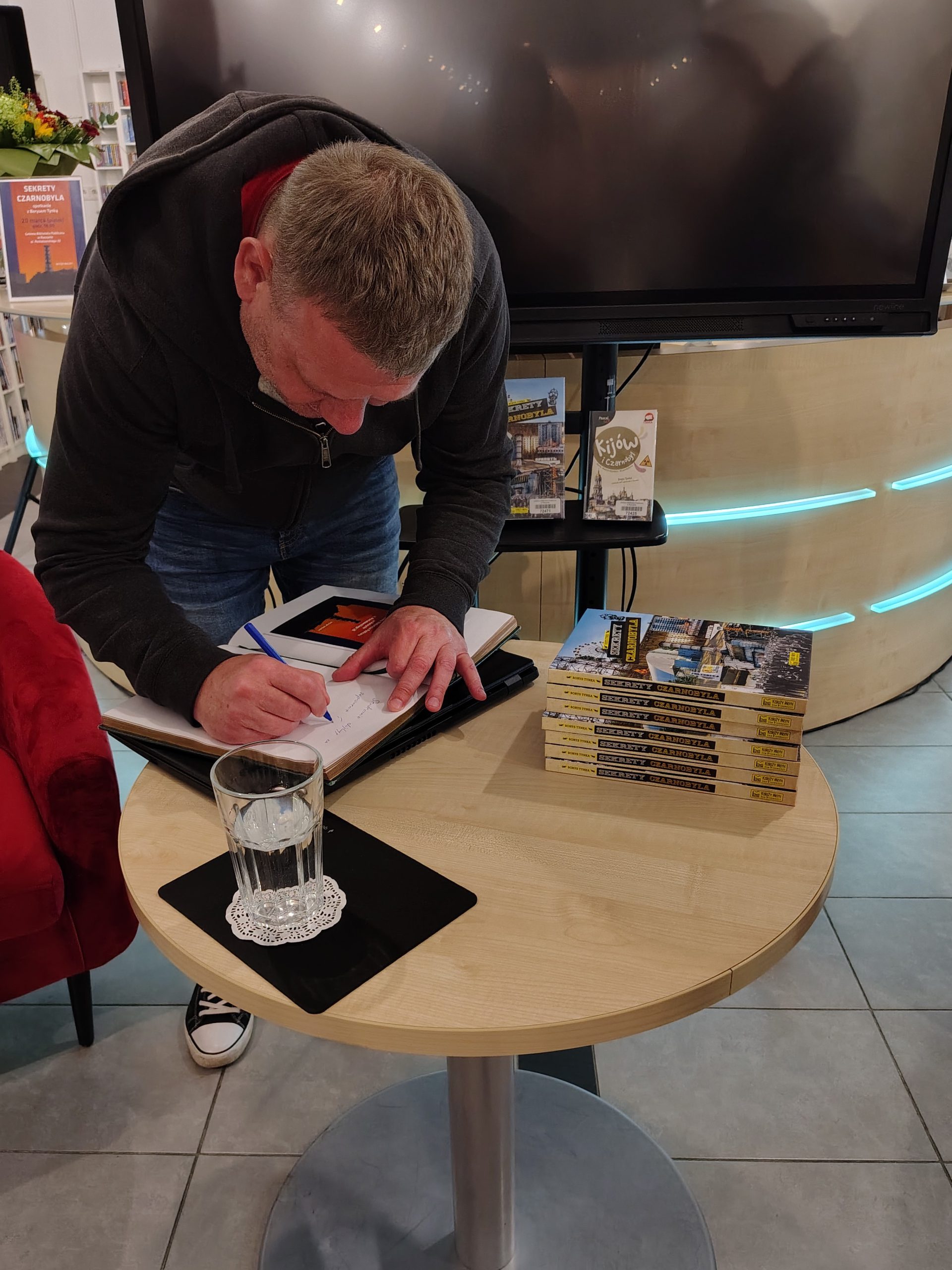 Autor wpisuje się do bibliotecznej księgi pamiątkowej