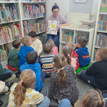 Bibliotekarka czyta książkę, dzieci siedzą na dywanie