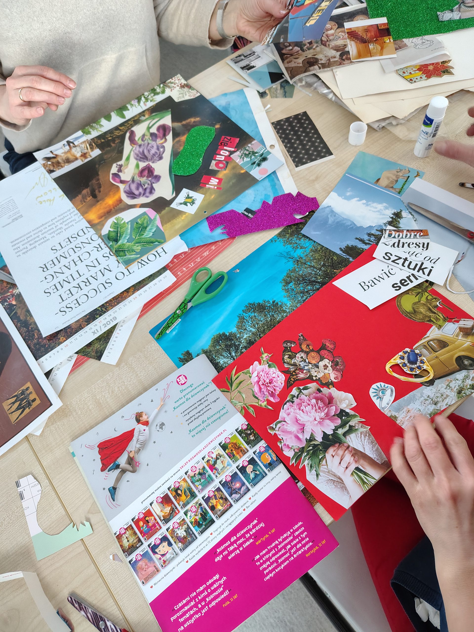 Powstający kolaż - widać dłoń układającą elementy na kolorowym papierze