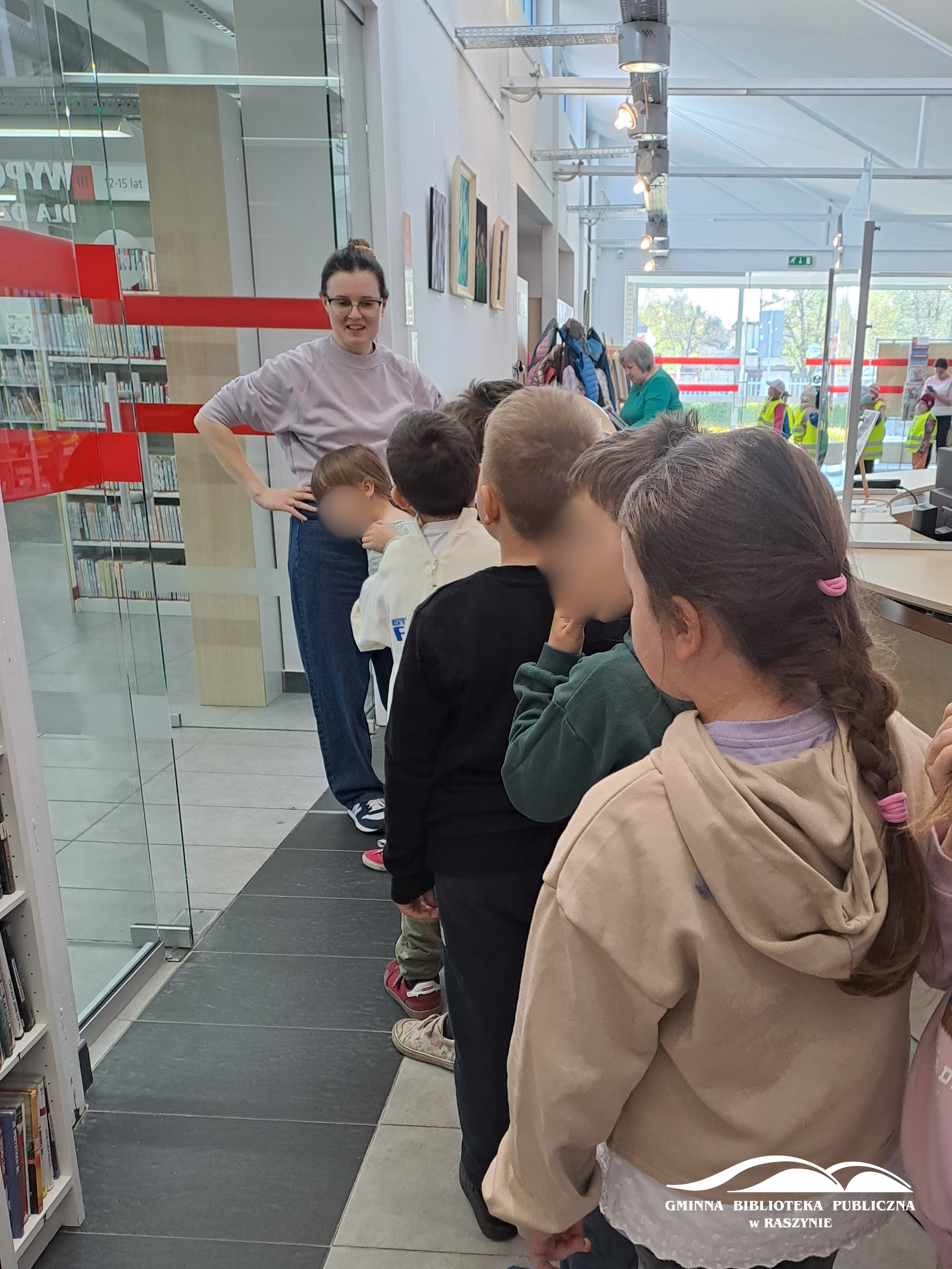Dzieci zwiedzają bibliotekę - widoczna bibliotekarka