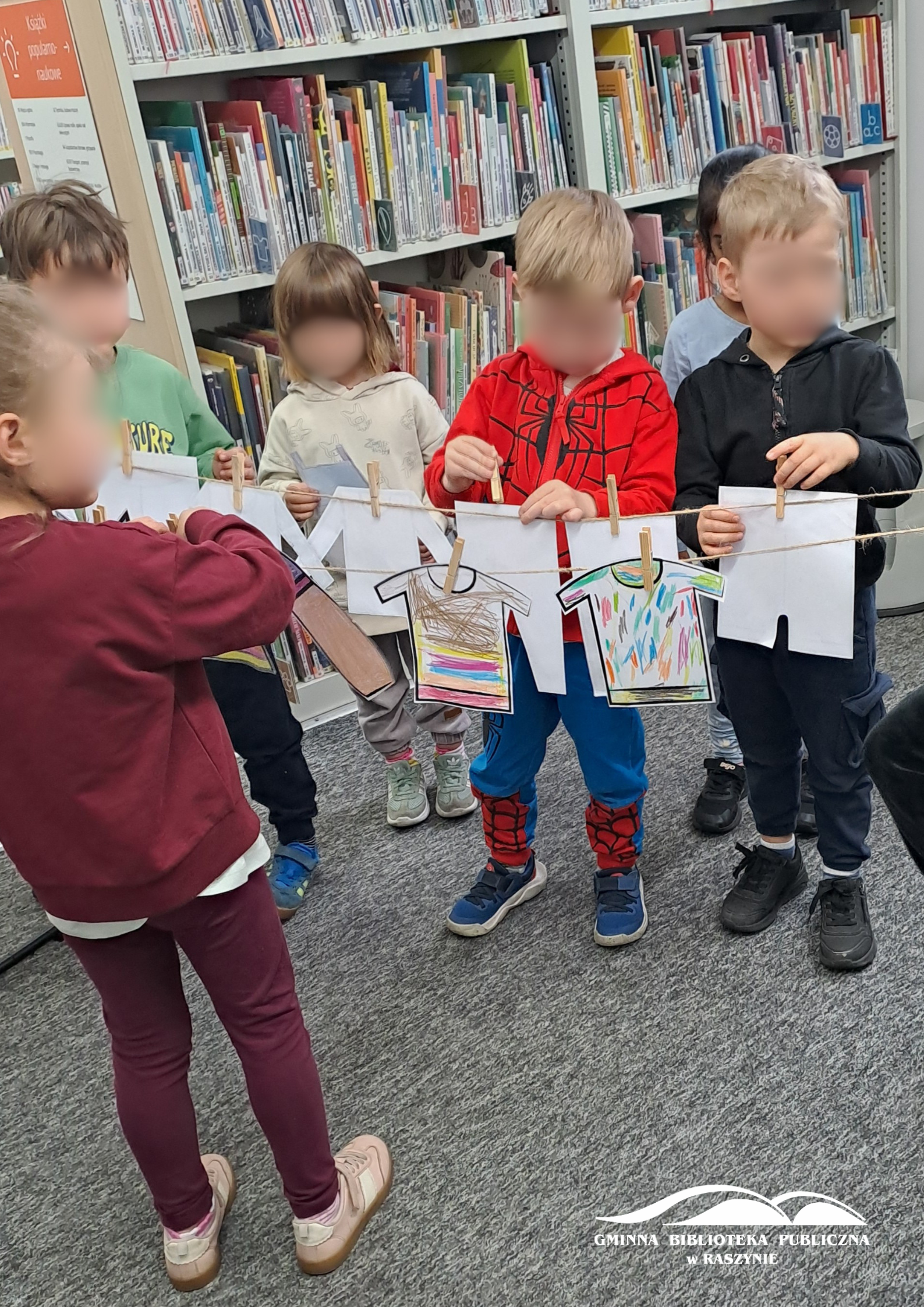 Dzieci podczas wieszania papierowego "prania" na sznurku