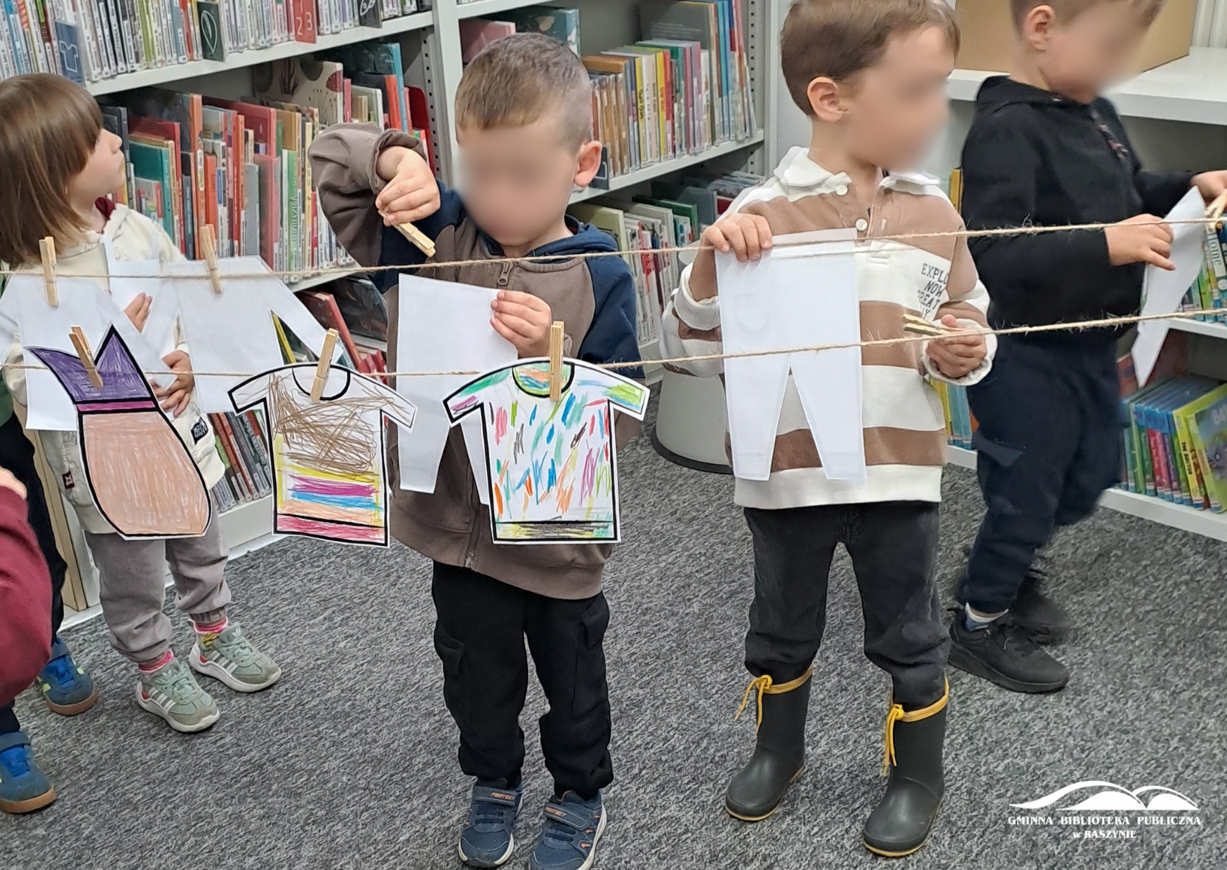 Dzieci wieszają papierowe "pranie" na sznurku