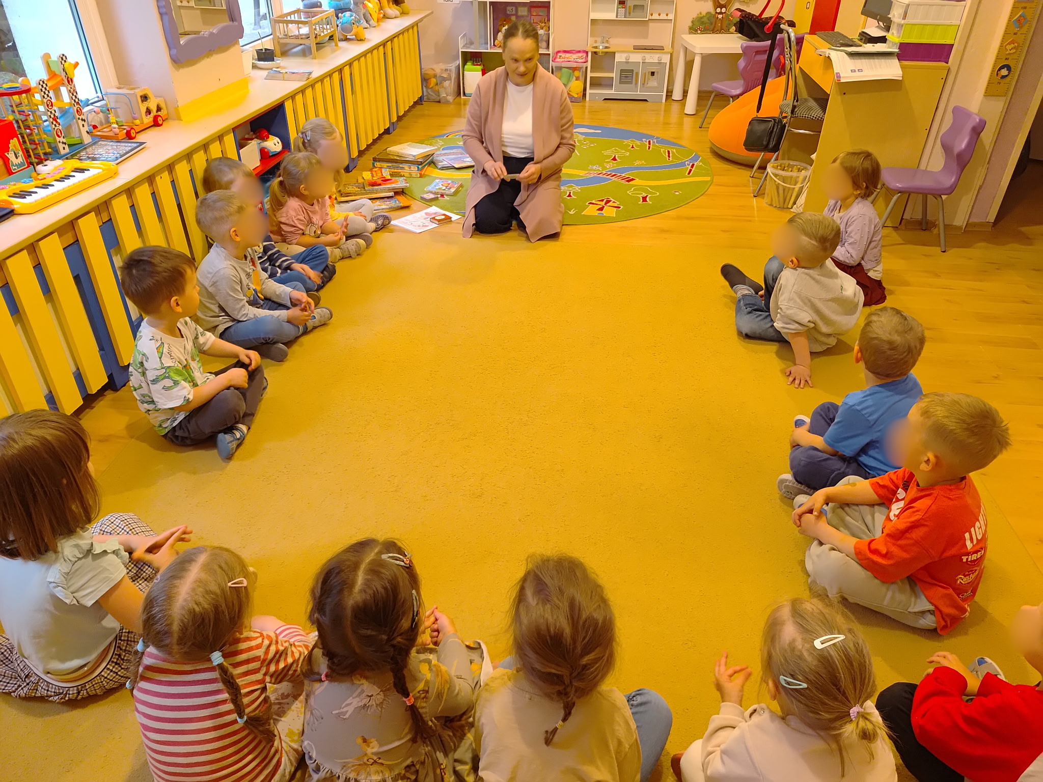 Bibliotekarka filii wraz z dziećmi siedzi w kółeczku