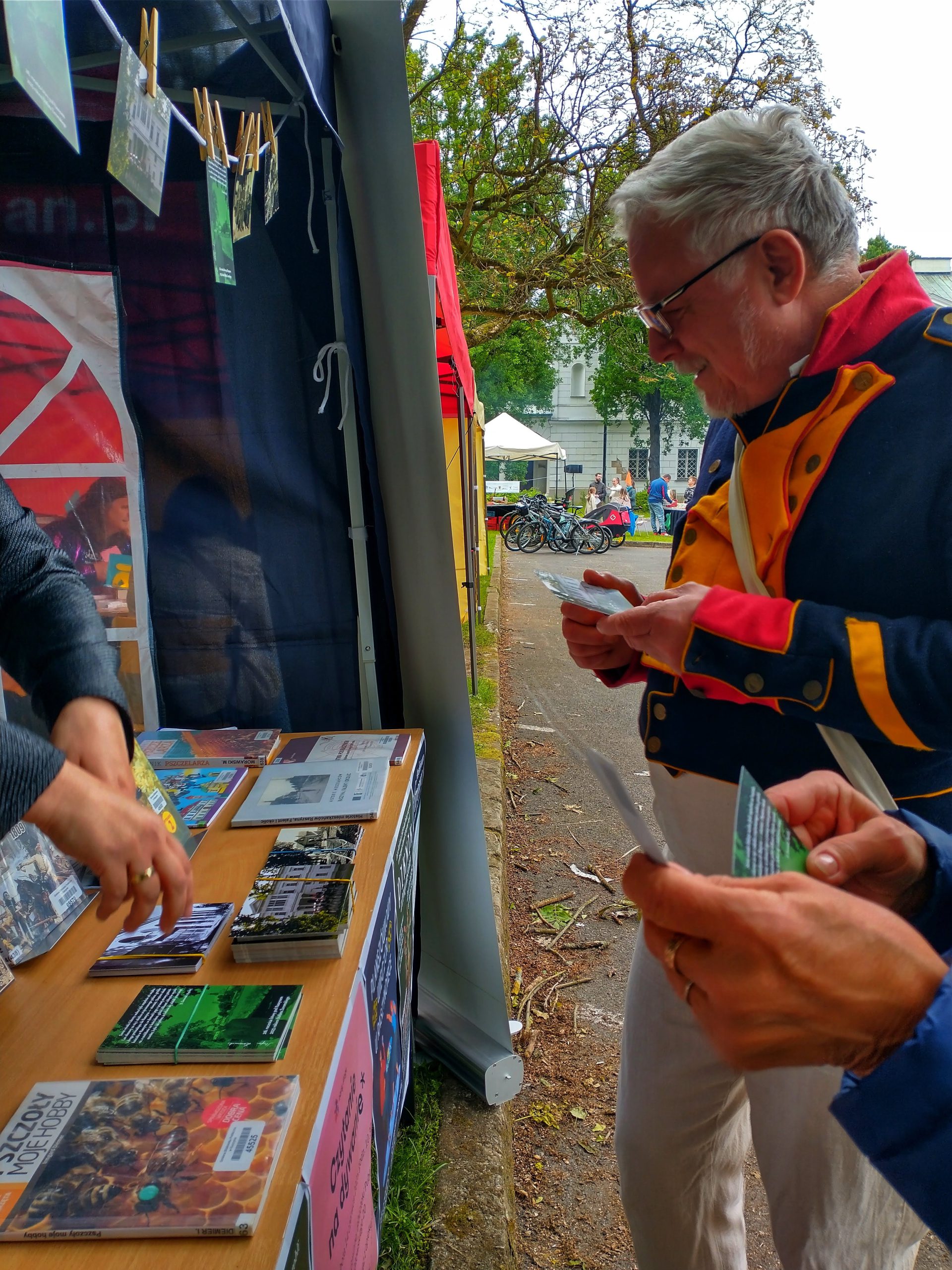 Rekonstruktor w stroju z epoki napoleońskiej ogląda pocztówki przy stoisku bibliotecznym