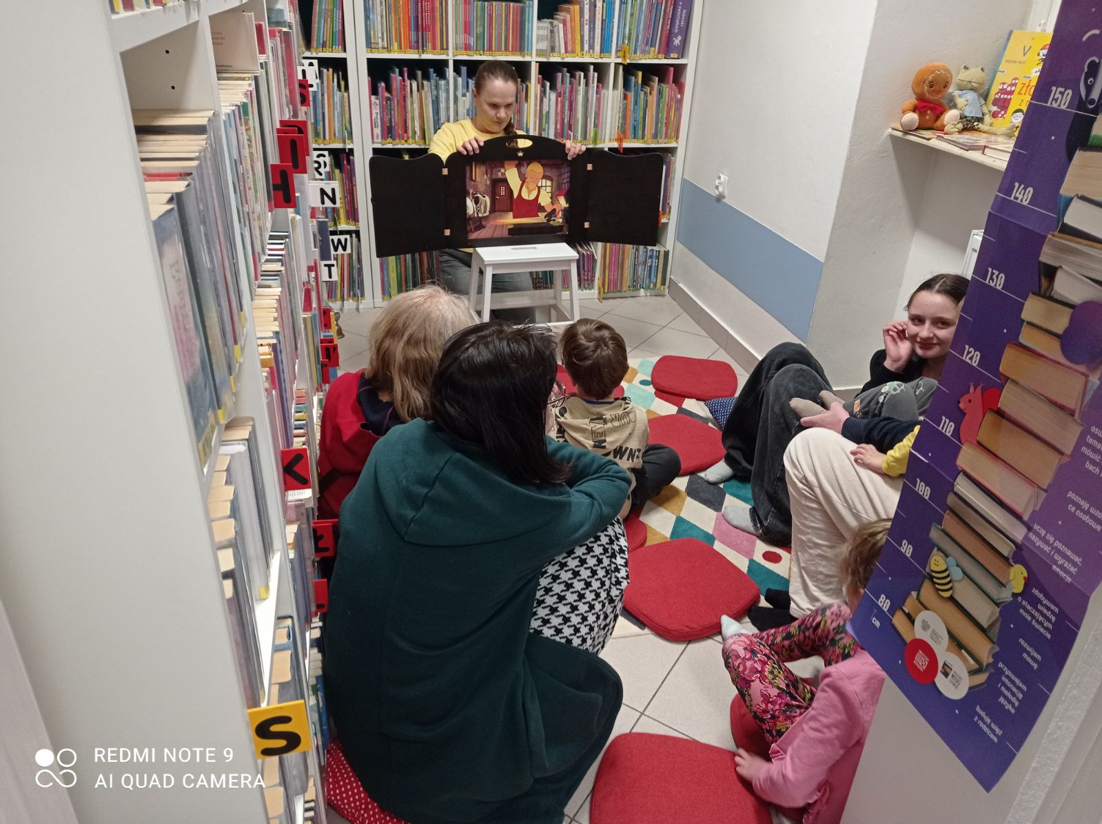 Bibliotekarka opowiada o bazyliszku, widoczna grupa dzieci