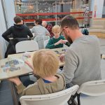 Uczestnicy wieczoru z grami planszowymi w bibliotece, siedzący przy stołach