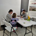 Rodzina z dzieckiem - uczestnicy wieczoru z grami planszowymi w bibliotece siedzą przy stole z rozłożonymi kartami