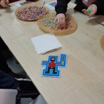 Zbliżenie na stół z jedną z prac i rozłożonymi koralikami