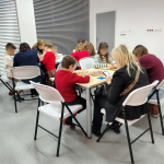 Grupy uczestników warsztatów siedzą i pracują nad swoimi podkładkami