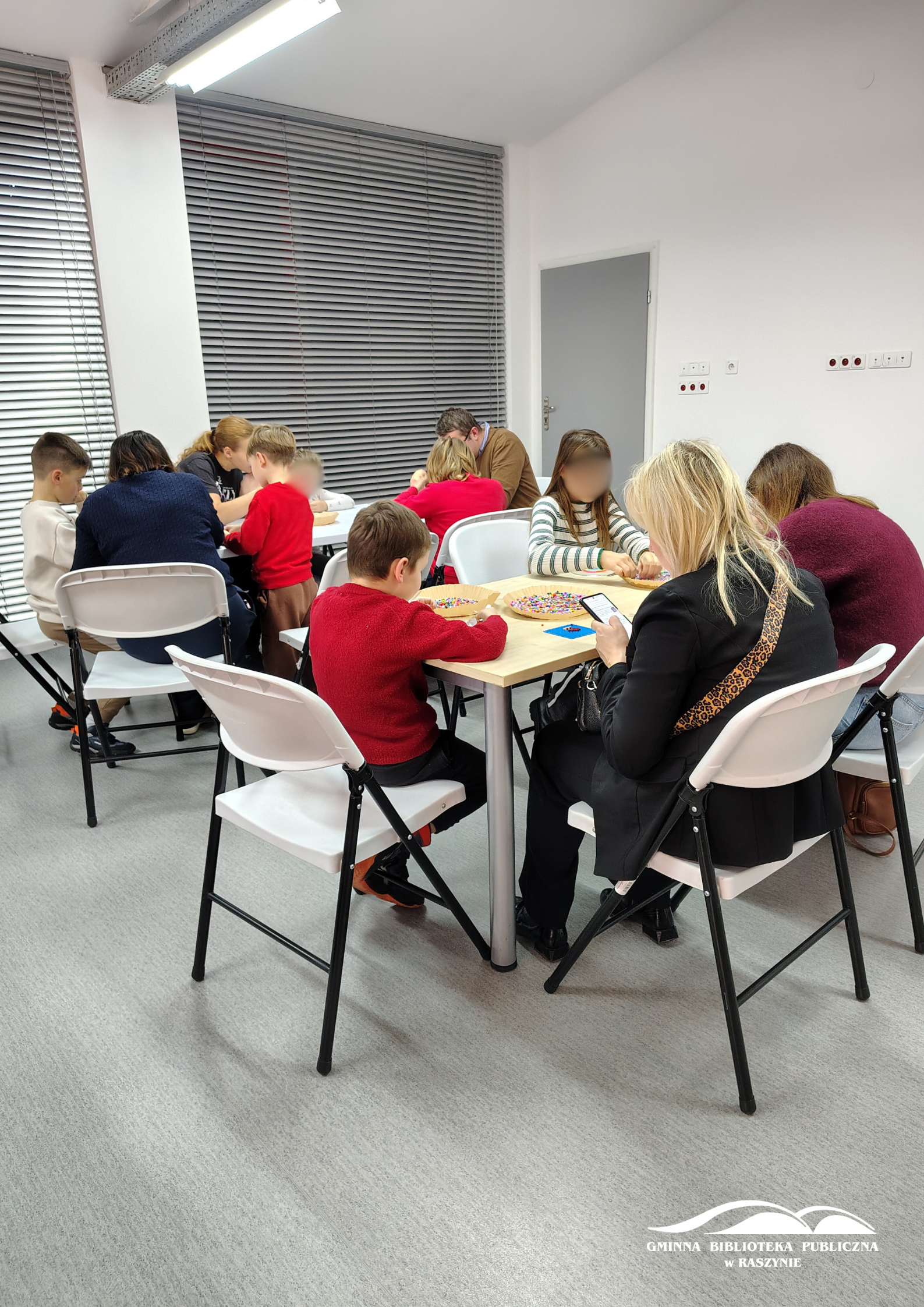 Grupy uczestników warsztatów siedzą i pracują nad swoimi podkładkami