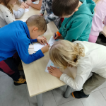 Dzieci pracują przy stole nad misiowymi pacynkami