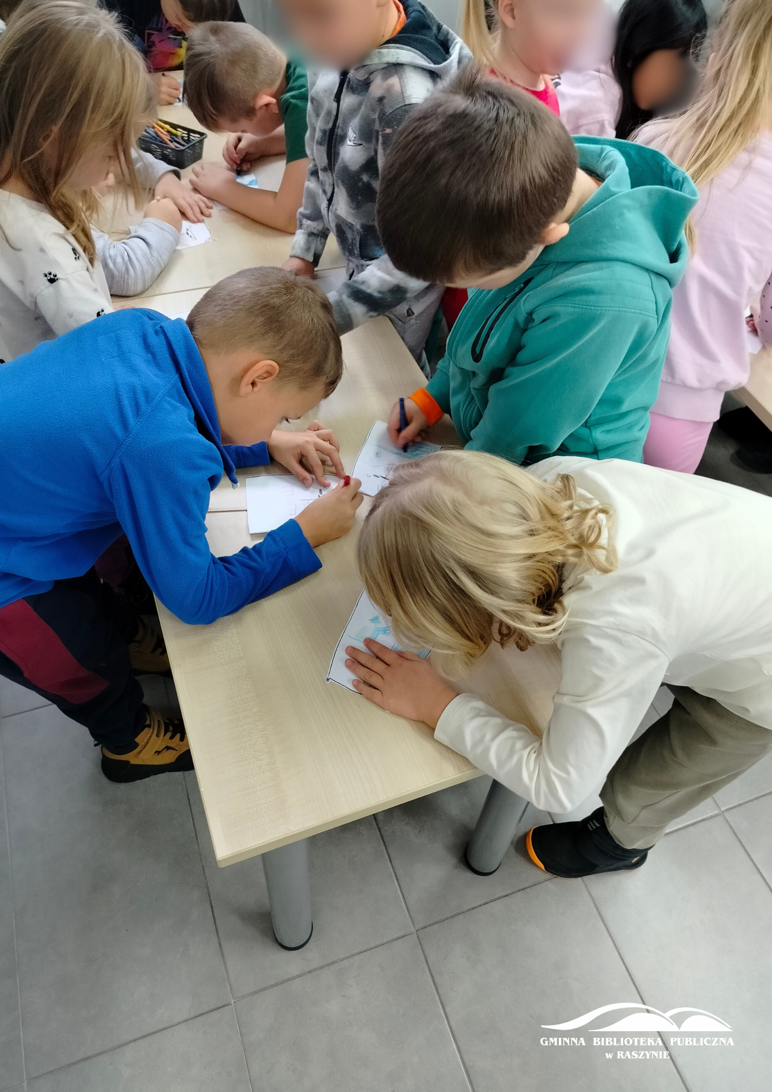 Dzieci pracują przy stole nad misiowymi pacynkami