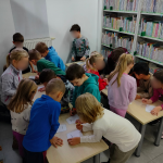 Dzieci kolorują misiowe pacynki przy stołach