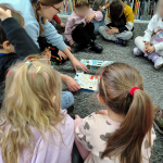 Bibliotekarka pokazuje ilustracje, dzieci siedzą dookoła i patrzą