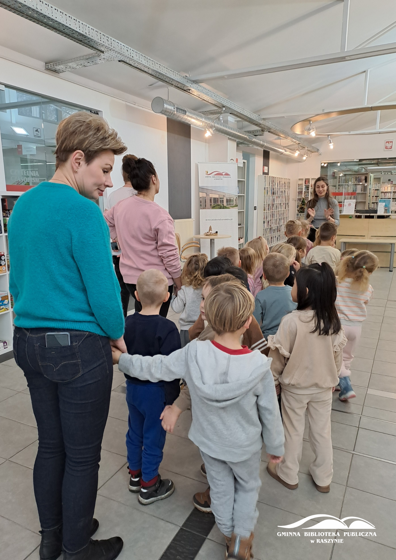 Grupa dzieci stoi w holu oczekując na rozpoczęcie lekcji bibliotecznej