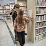 Grupa dziewczynek podczas odczytywania zagadki z regału bibliotecznego