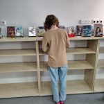 Dziecko przegląda wystawkę mang na regale