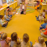 Bibliotekarka filii wraz z dziećmi siedzi w kółeczku